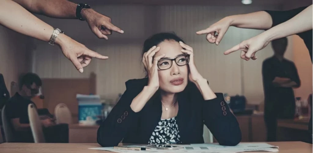 A woman at work with people pointing their fingers at her, demanding work and requests.